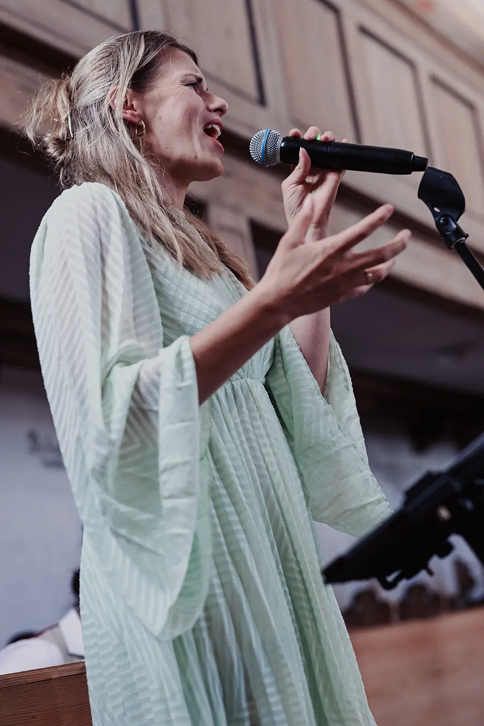 Sängerin in der Kirche mit Mikrophon im grünen Kleid.
