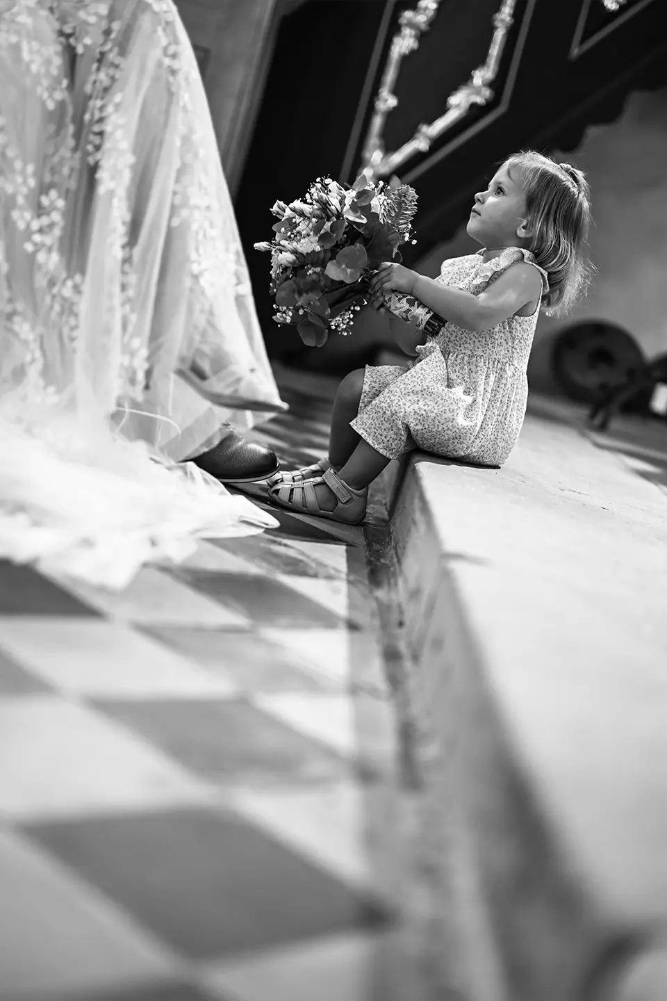 Kirchliche Trauung mit kleiner Tochter, die auf dem Boden vor den Eltern sitzt und den Brautstrauß hält.