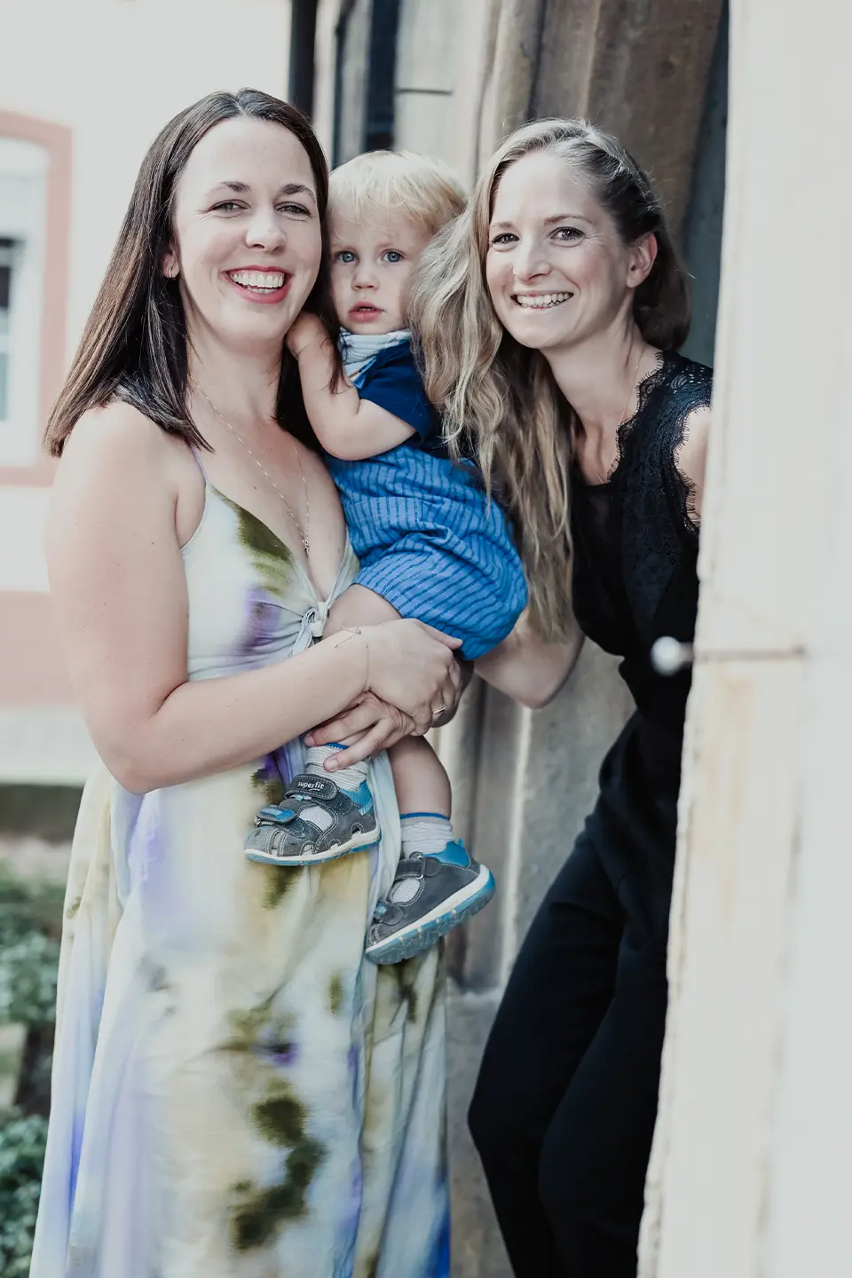 Zwei Frauen mit Baby auf dem Arm lachen auf einer Hochzeitsfeier.