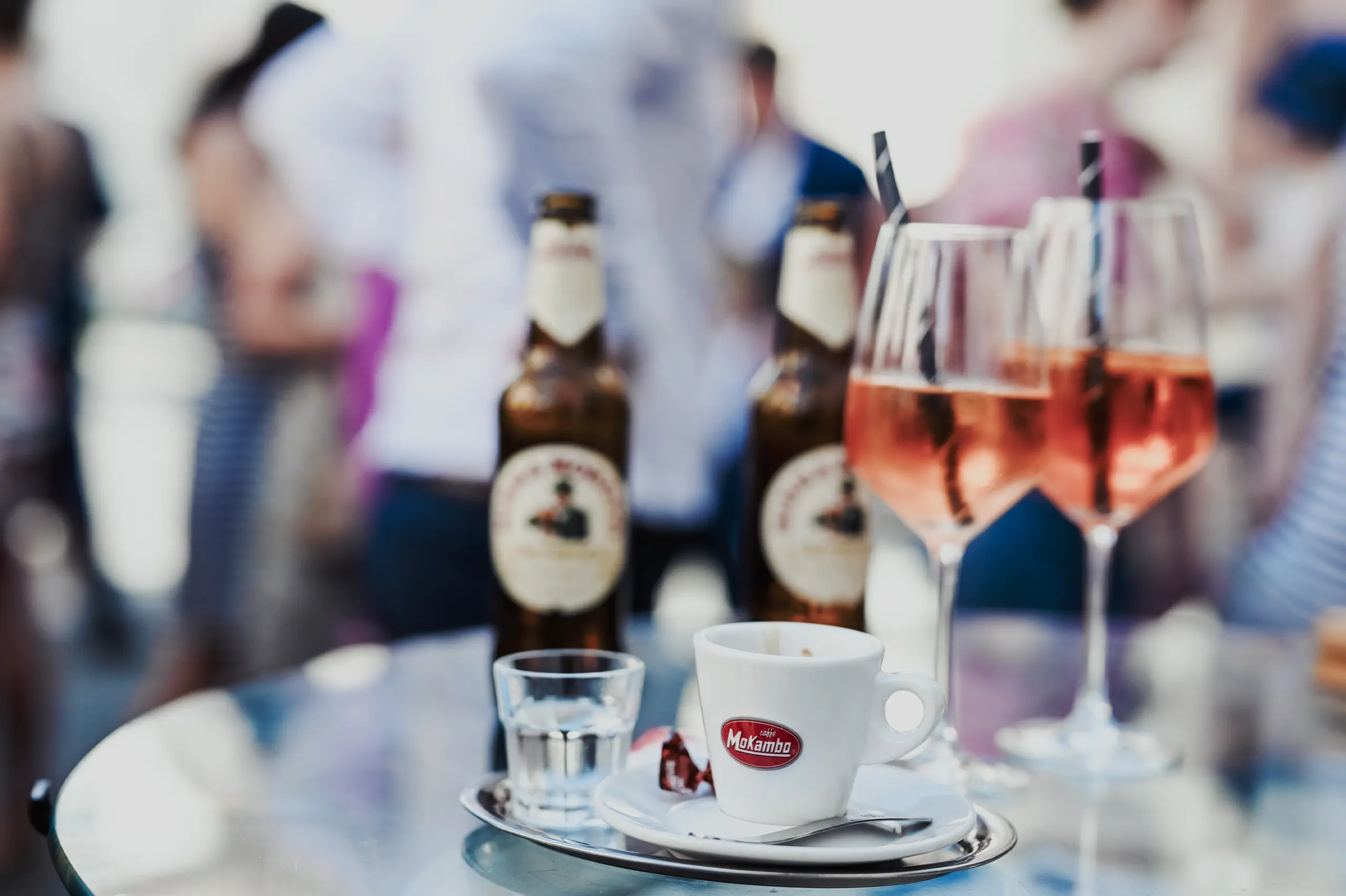 Aperol Gläser, Kaffetasse und Wasserglas auf einem Stehtisch.