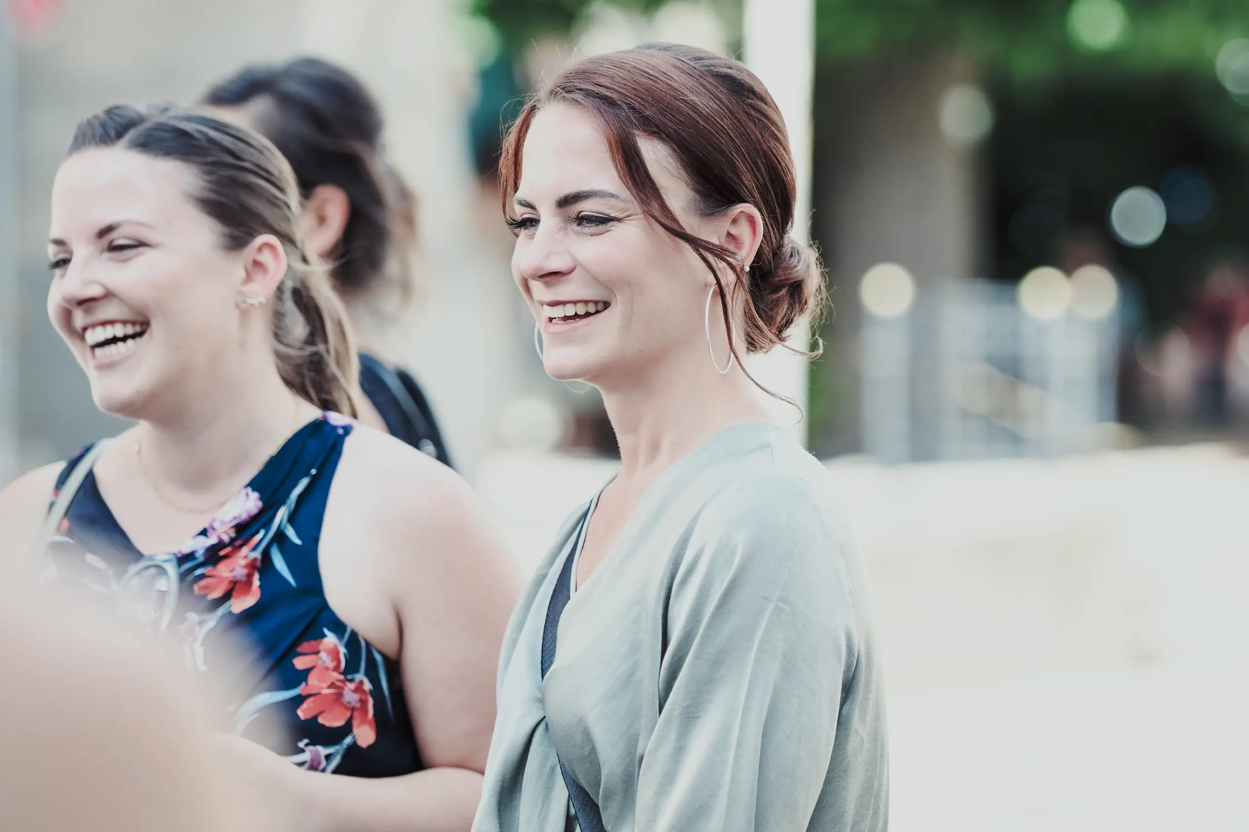Portrait einer Frau die lacht mit grüner Jacke.