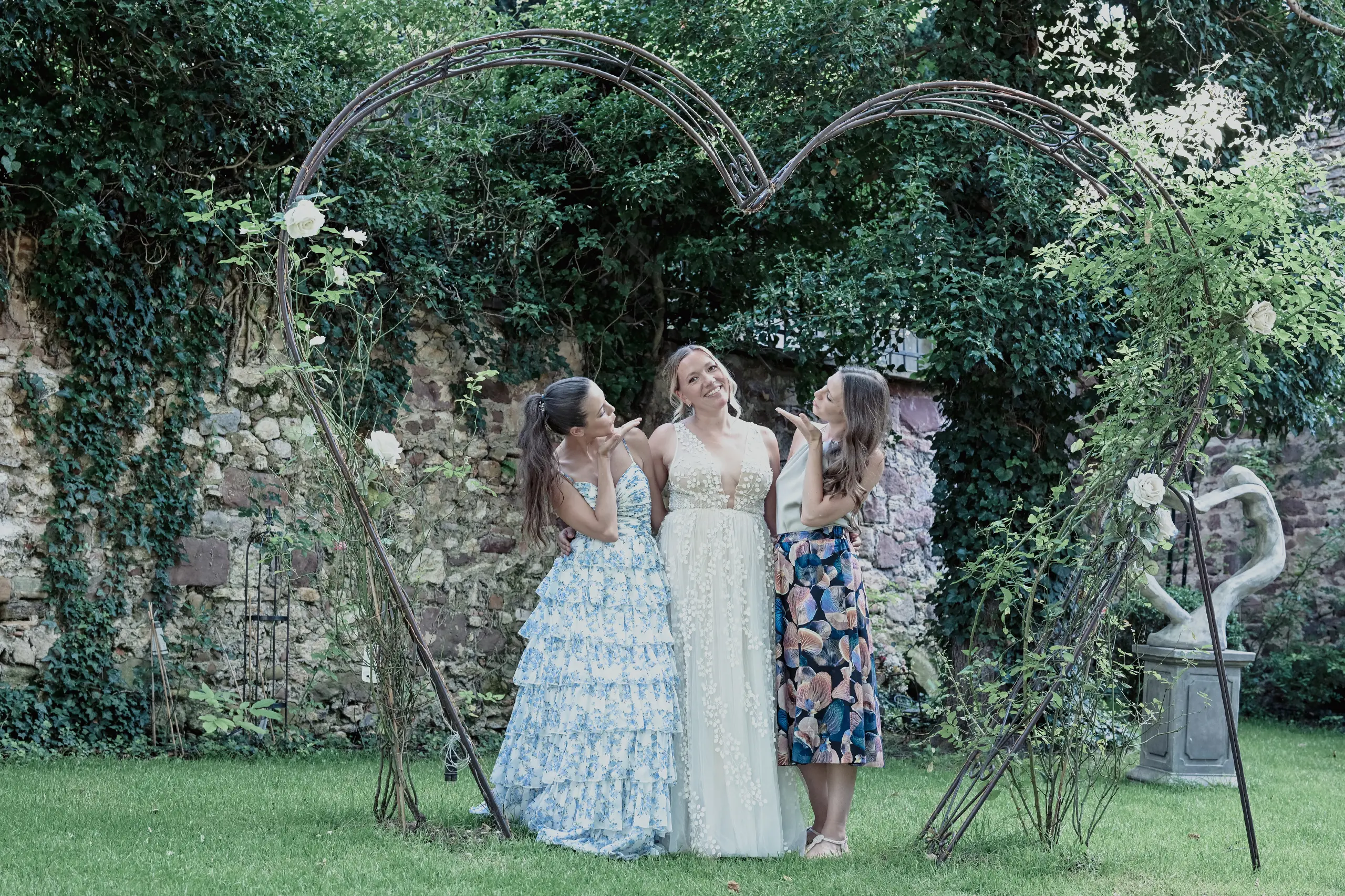 Gruppenfoto zwei Frauen mit Braut unter einem Herz.