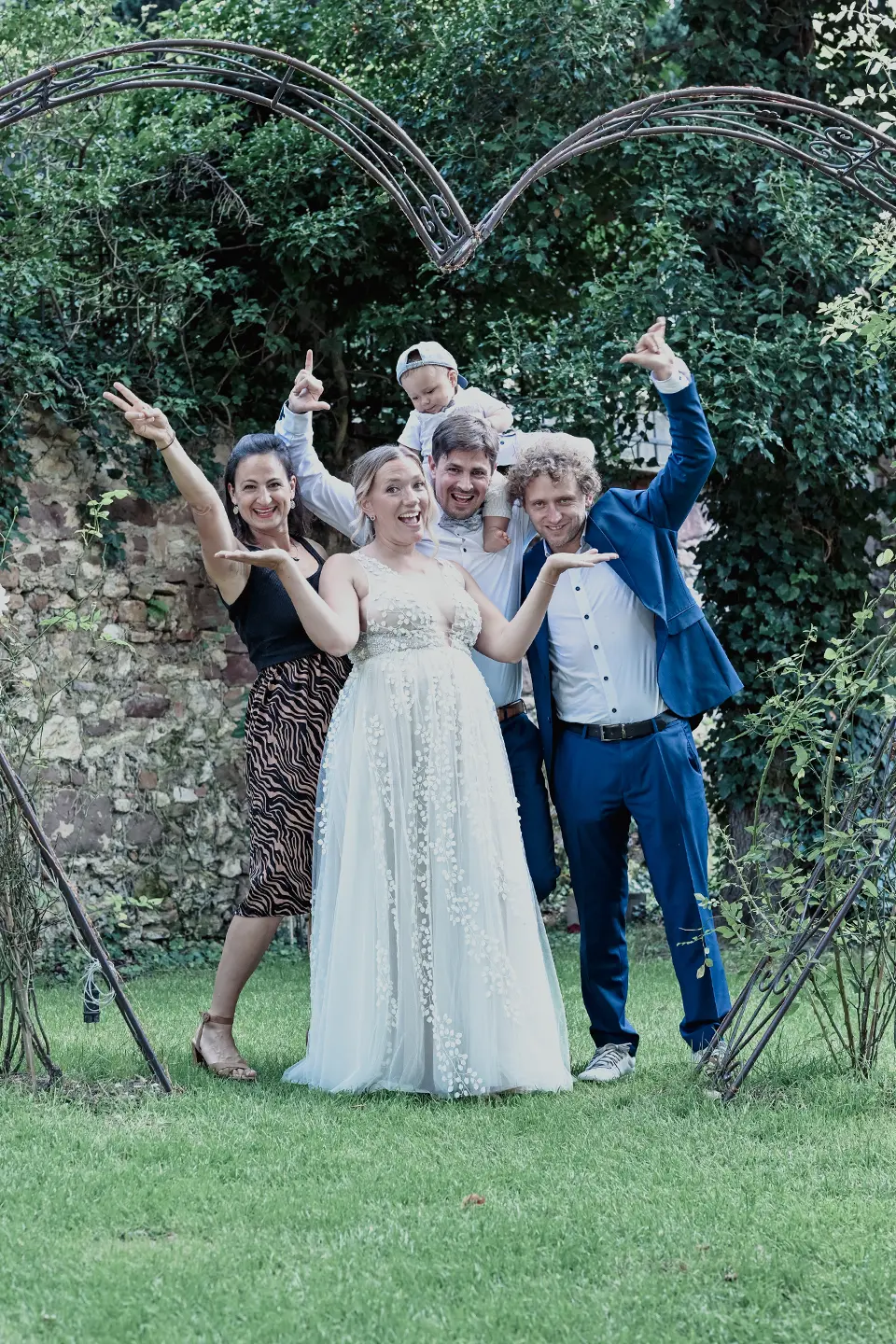 Lustiges Hochzeitsgruppenfoto mit Baby im Grünen.