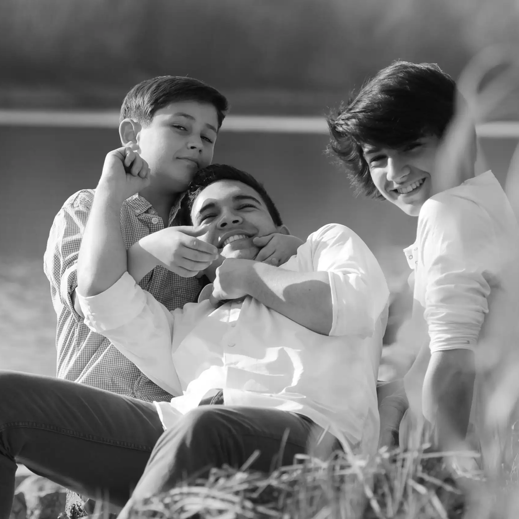 Familienfoto von drei Jungen am Rhein, kabbeln sich und haben Spass.
